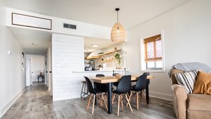 Una cocina moderna con armarios blancos, una mesa de comedor de madera y sillas negras.