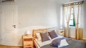 A bedroom with a bed, wooden headboard, bedside tables, a lamp, and a window with curtains. - Lovely home in Gizycko with WiFi (Gizycko)