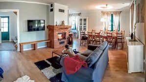 A living room with a fireplace, a television, and a dining area with chairs and a table. - Lovely home in Gizycko with WiFi (Gizycko)