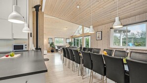 Une cuisine moderne avec des murs en bois, un îlot central et un coin repas doté de chaises noires.