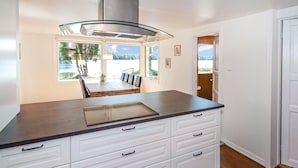 A modern kitchen with a large island, white cabinetry, and a view of a dining area with a table and chairs. - Nice home in Hallaryd with kitchen (Hallaryd)