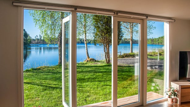 A room with large sliding glass doors leading to a grassy area with trees and a lake view. - Nice home in Hallaryd with kitchen (Hallaryd)