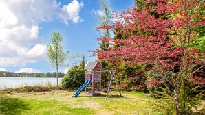 A playground with a slide and a small pavilion, surrounded by trees and a lake. - Nice home in Hallaryd with kitchen (Hallaryd)