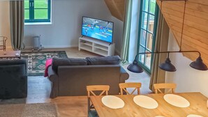 Un salon avec un canapé, un téléviseur et une table à manger avec des chaises.