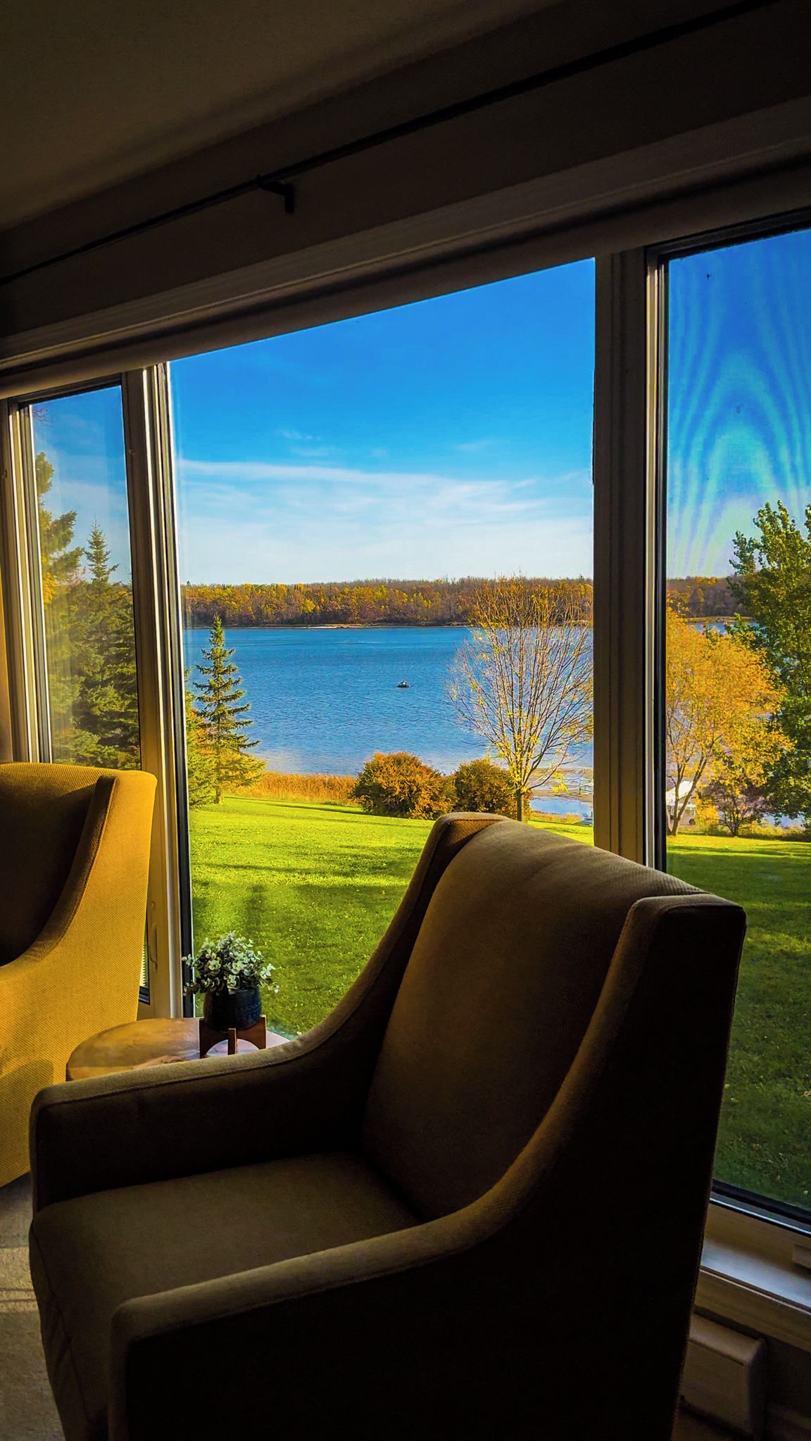 Una habitación con un ventanal que ofrece vistas a un lago y un bosque.