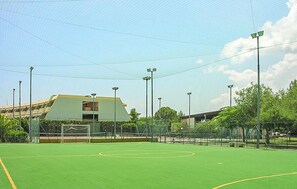 Un terrain de sport avec des poteaux de but, entouré d’une clôture, et un bâtiment en arrière-plan.