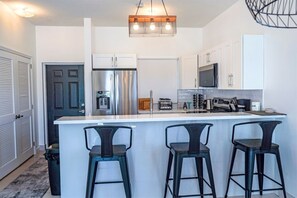 A modern kitchen with a central island, stainless steel appliances, and bar stools.