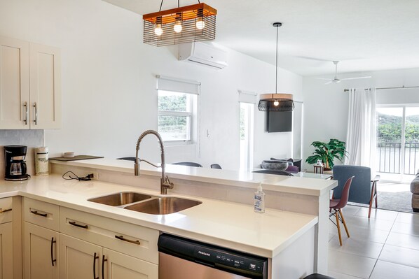 A modern kitchen with a dishwasher, a coffee maker, and a sink. - Flamingo Lake Villas | Turks and Caicos Islands (Providenciales)