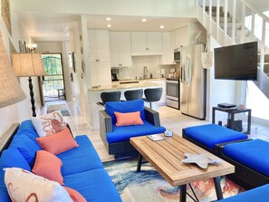 A modern living room with a blue sofa set, a wooden coffee table, and a kitchen in the background. - *AMAZING LOCATION*  Turtle Bay  (Kahuku)