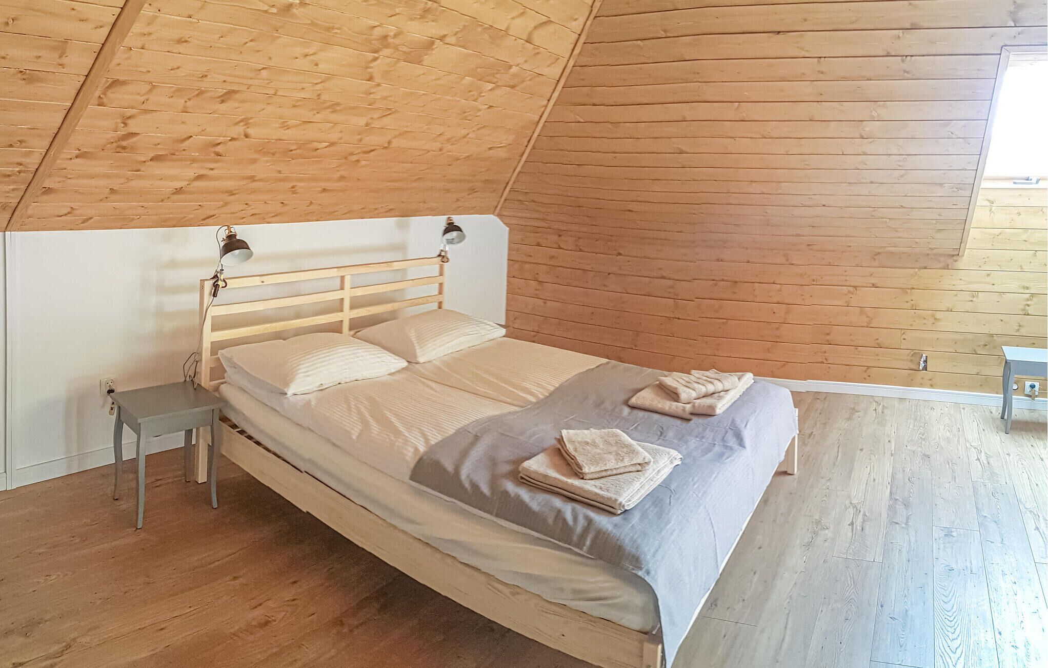 A single bed in a room with wooden walls and a sloped ceiling.