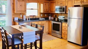 Una cucina in stile baita in legno con tavolo, sedie, frigorifero, forno a microonde e forno.