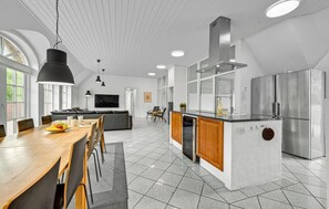 Een moderne keuken met een centraal eiland, roestvrijstalen apparatuur en een eethoek met een houten tafel en stoelen.