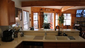 A kitchen with wooden cabinets, a dishwasher, a sink, and a television mounted on the wall. - Relaxing 3 bedroom retreat in the pines , come relax in tranquility,<br>  (Pinetop)