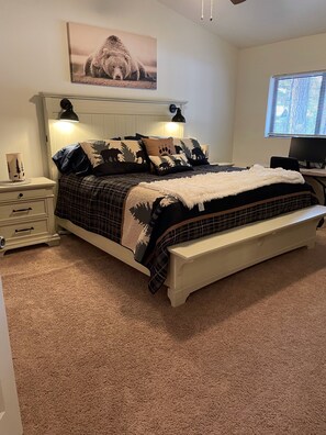A bedroom with a bed, bedside tables, a lamp, a desk, and a window.