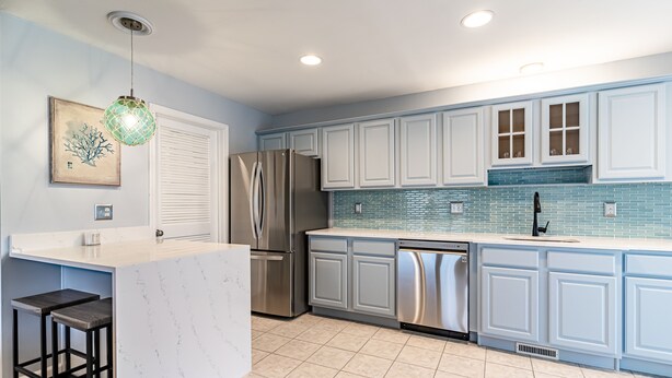 A modern kitchen with white cabinets, a stainless steel refrigerator, a dishwasher, and a marble countertop. - Seaside Park 3BR Beach Home – Family-Friendly, Walk to Beach + Peloton + Badges (Seaside Park)