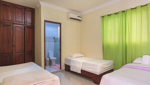 A hotel room with two single beds, a wooden wardrobe, a bathroom with a toilet and sink, and a green curtain. - Family 1bedroom Apartment 15 Minute to the Airport (Santo Domingo Este)