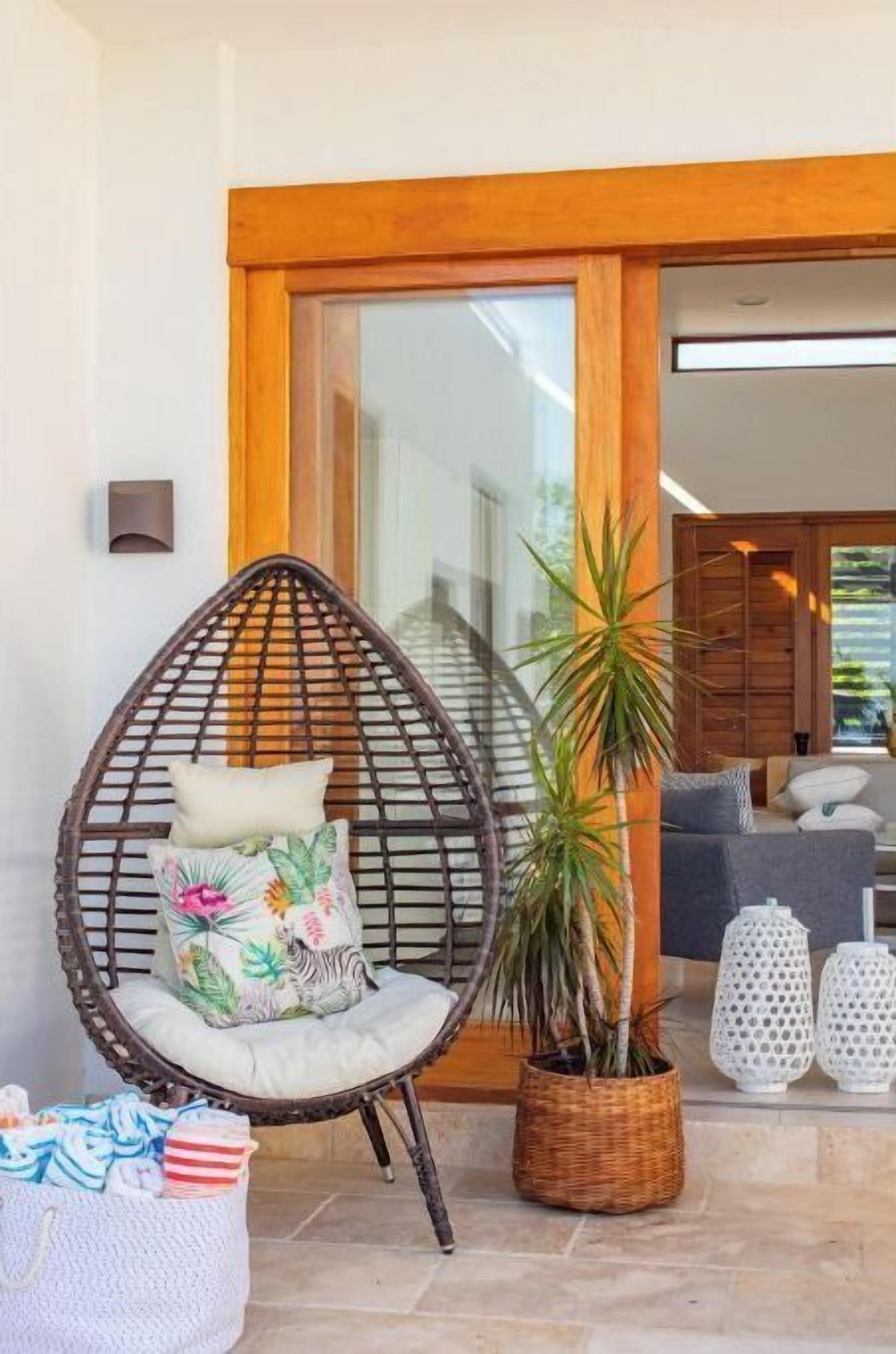 A wicker chair with cushions, a potted plant, and a small table with towels.
