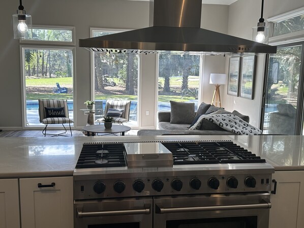 Enjoy cooking in the spacious kitchen with a range and oven, and take in the view of the outdoor area with a pool and patio furniture.