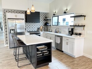 Eine moderne Küche mit Kochinsel, Edelstahlgeräten und einer strukturierten Spritzschutzwand.