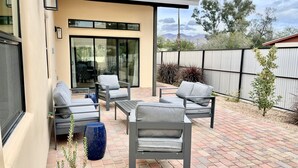 Eine Terrasse mit Gartenmöbeln, einem Glastür-Eingang und Blick auf die umliegende Landschaft.