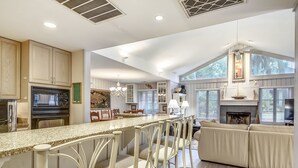 A spacious kitchen with a large island, bar stools, and a fireplace. - Charming Sea Pines Retreat – 4th Row from the Beach with EV Charger (Hilton Head Island)
