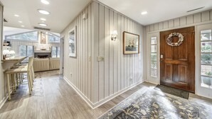A hallway with a wooden door, a framed picture, and a bench. - Charming Sea Pines Retreat – 4th Row from the Beach with EV Charger (Hilton Head Island)