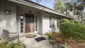 A house with a front porch, a bench, and potted plants. - Charming Sea Pines Retreat – 4th Row from the Beach with EV Charger (Hilton Head Island)