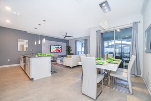 Enjoy a spacious open-plan living area with a dining space and kitchen, featuring a comfortable sofa set and flat-screen TV.