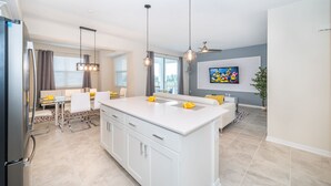Una cucina moderna con isola centrale, mobili bianchi e illuminazione a sospensione.