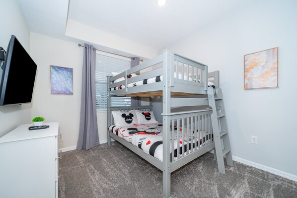 A bunk bed with Mickey Mouse themed bedding, a TV on a cabinet, and a small plant. - CN207 Storey Lake Condo 2 Bed 2 bath Free Waterpark (Kissimmee)