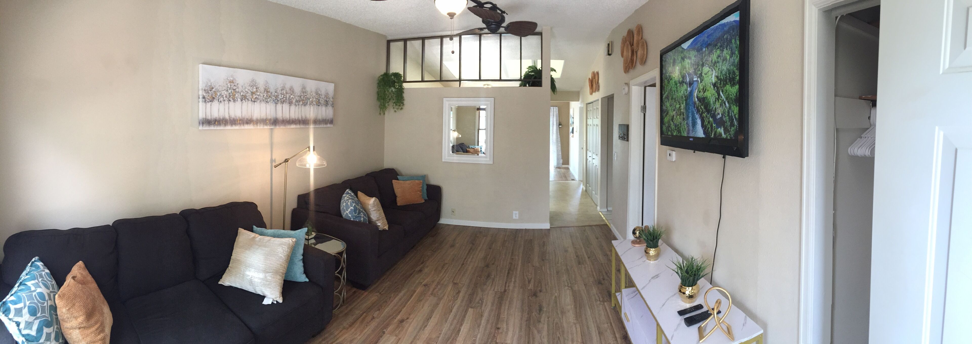 A modern living room with a dark-colored sofa, a glass coffee table, and a white console table with decorative items.