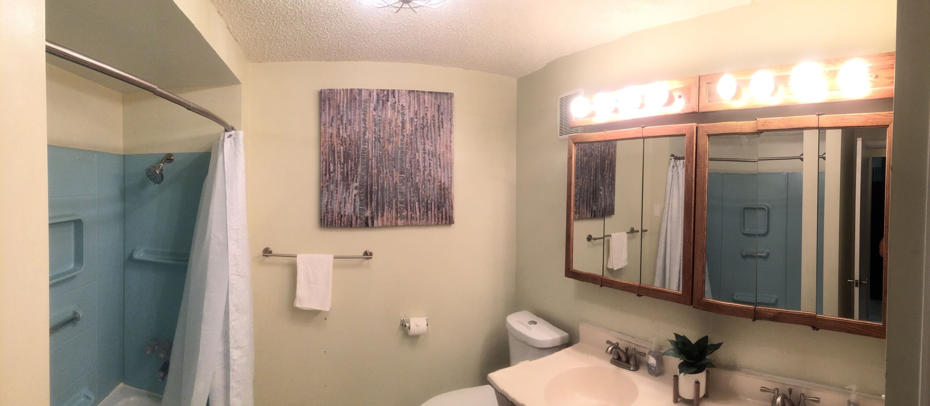 Un bagno con doccia, toilette, lavandino e un ampio specchio illuminato.