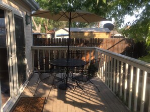 A deck with a round table and chairs, a pergola with an umbrella, and a white picket fence. - ➳The EASY of COS- Next to Downtown & OCC/Manitou!➳ (Colorado Springs)