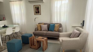 Un salon moderne comprenant un canapé, deux fauteuils, une table basse et un coin repas avec des chaises et une table.