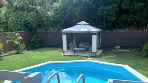Une piscine avec une terrasse en bois et une clôture blanche.