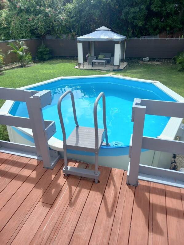 A swimming pool with a wooden deck and a white fence.