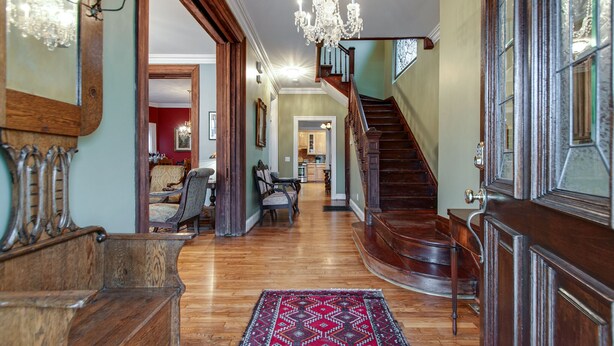 A grand hallway with a wooden staircase, a chandelier, and a dining area with chairs and a table. - Nashville Historic Edgehill/Music Row/ Gulch Home (Nashville)