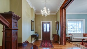 A spacious living room with hardwood floors, a chandelier, a sofa, and a large window. - Nashville Historic Edgehill/Music Row/ Gulch Home (Nashville)