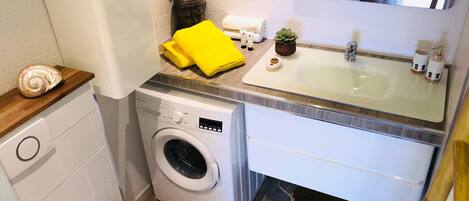 A compact bathroom with a washing machine, a sink, and a toilet.