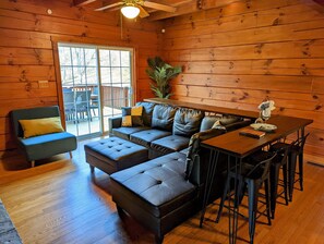 Interior acolhedor de uma cabana com sofá de canto, uma mesa pequena e um espaço de bar.