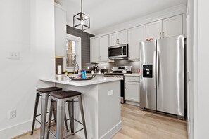 A modern kitchen with white cabinets, stainless steel appliances, and a central island with stools.