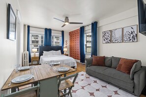 A hotel room with a bed, a sofa, a dining table set for two, and artwork on the walls. - Charming Studio - Downtown Seattle - 98 Walk Score (Seattle)
