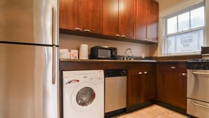 A kitchen with stainless steel appliances, wooden cabinets, a microwave, and a dishwasher. - Charming Belltown Corner Studio (Seattle)