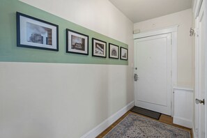 A hallway with a green wall, a white door, and four framed pictures. - Charming Studio - Downtown Seattle - 98 Walk Score (Seattle)