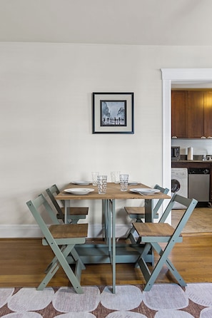 A dining area with a round table, chairs, and a framed picture on the wall.