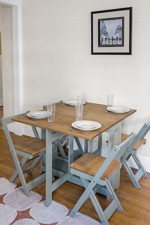 A dining table with four chairs, a framed picture on the wall, and a patterned rug on the floor. - Charming Studio - Downtown Seattle - 98 Walk Score (Seattle)