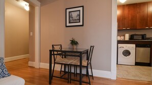 A dining area with a table and chairs, a washing machine, and a microwave in the kitchen. - Charming Belltown Corner Studio (Seattle)