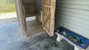 Una struttura in legno aperta con una panchina di fronte a una casa.