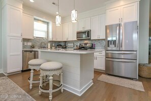 Enjoy cooking in this well-equipped kitchen with a central island, barstools, and stainless steel appliances.