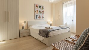 A modern bedroom with a bed, bedside tables, a wall-mounted light fixture, and a window with curtains.